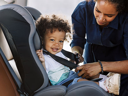 mom buckling her child in a car seat