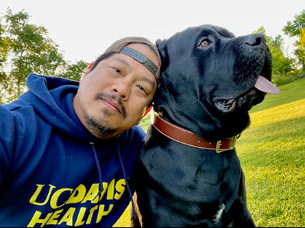 man smiling with his large black dog in a park