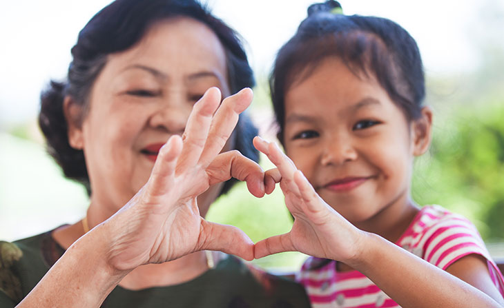 older woman and young girl making a heart with their hands